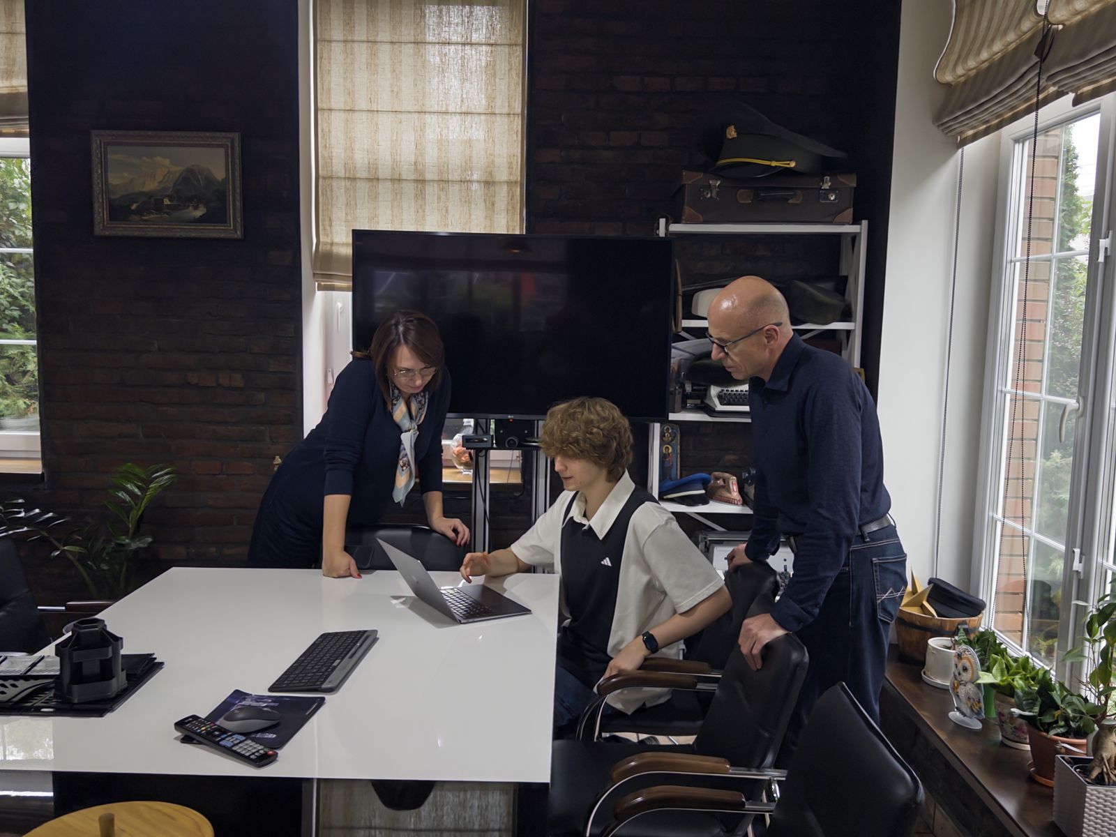 Three people around a laptop at a meeting table in the Olteks office