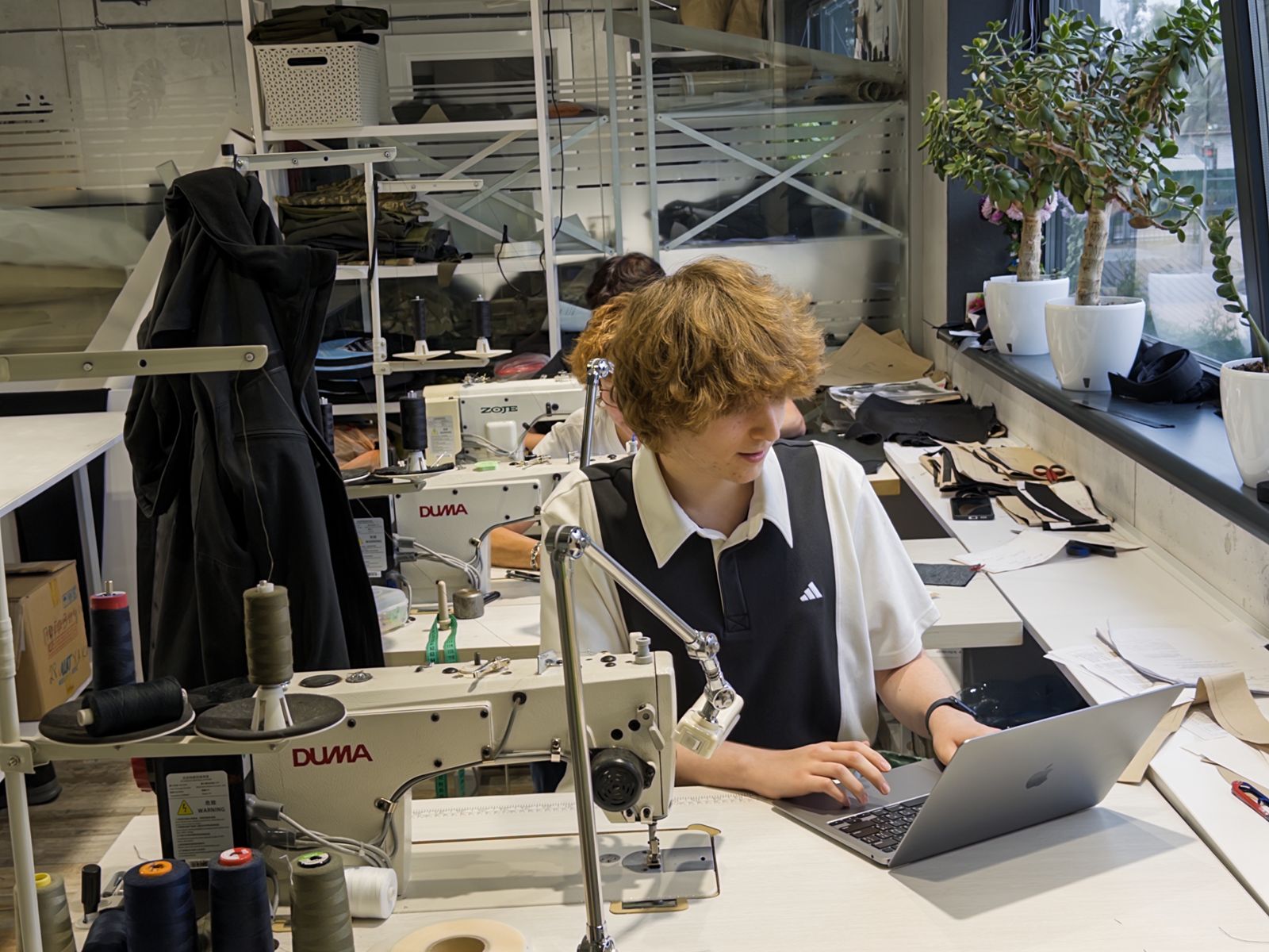 A SoilTwin team member working on a laptop at a sewing station on the Olteks production floor
